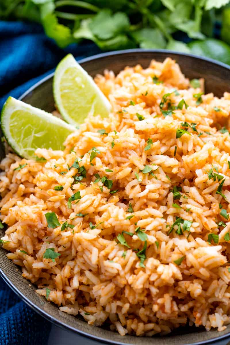 Spanish Rice with two lime wedges in it in a dark bowl. 