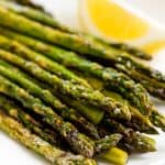 Grilled Asparagus on a white plate with a lemon wedge.