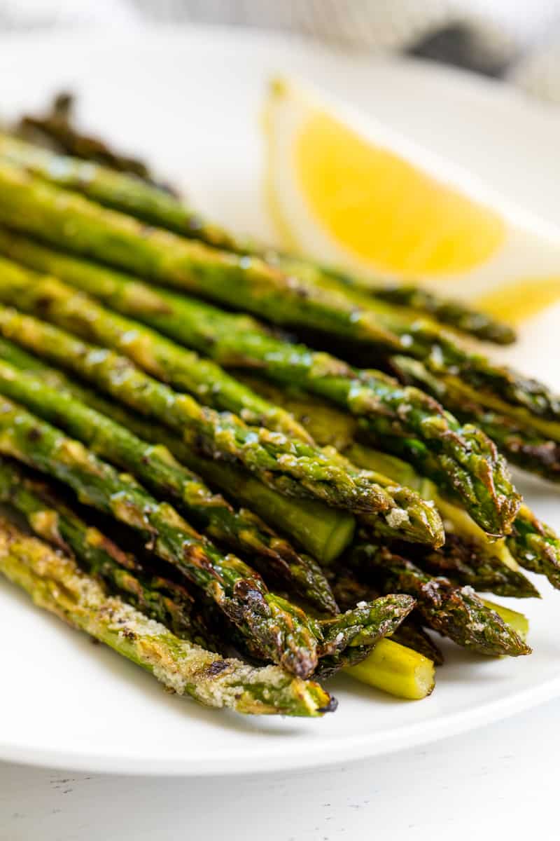 Grilled Asparagus on a white plate with a lemon wedge.