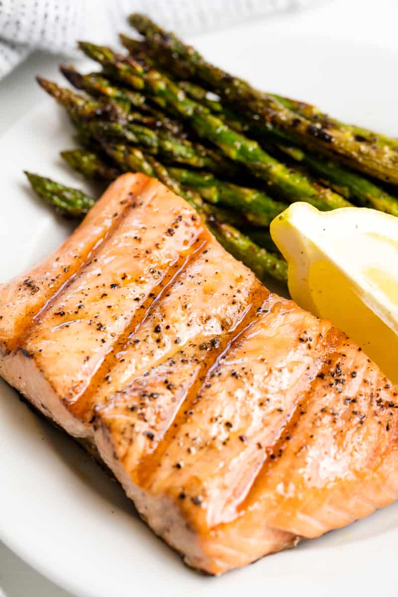 Grilled Salmon on a white plate with asparagus and a lemon wedge.
