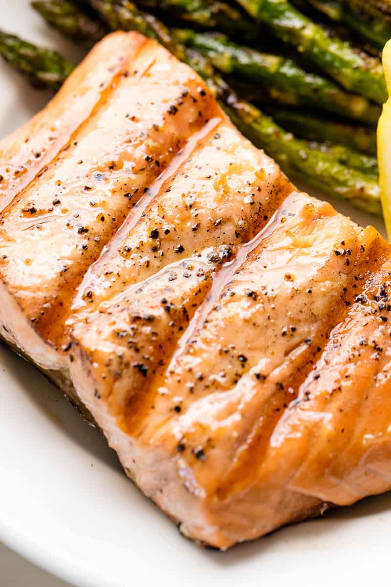 Close up of Grilled Salmon on a white plate with asparagus and a lemon wedge.
