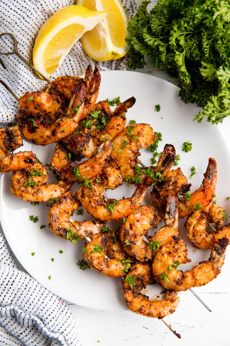 Bird's eye view of Grilled Shrimp on skewers on a white plate. 