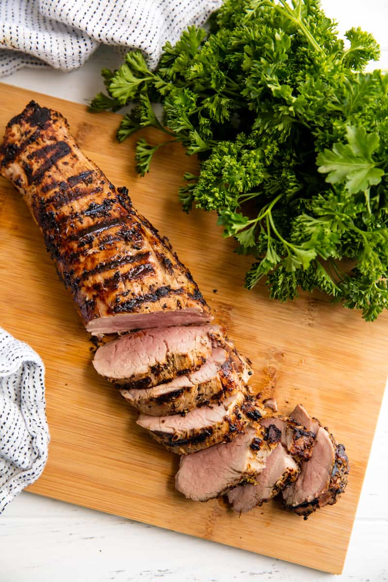 A Grilled Pork Tenderloin cut into slices on a cutting board