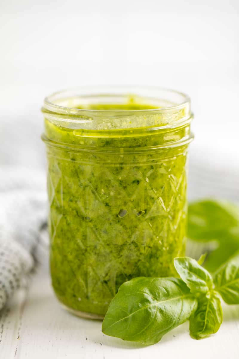 Fresh Simple Basil Pesto in a mason jar surrounded by sprigs of basil
