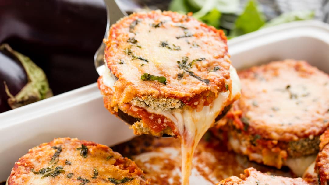 Eggplant parmesan being dished out of a pan