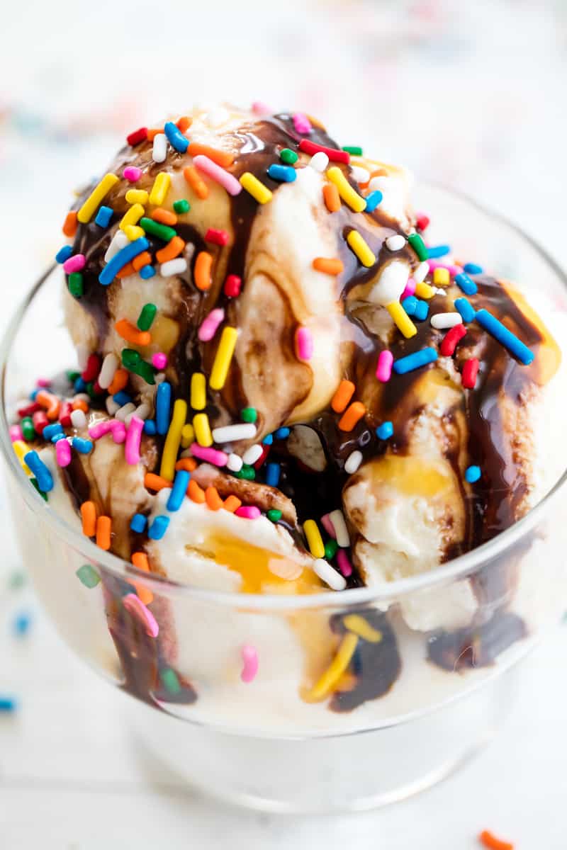 Homemade Ice Cream in a glass dish with chocolate sauce, caramel and colorful sprinkles