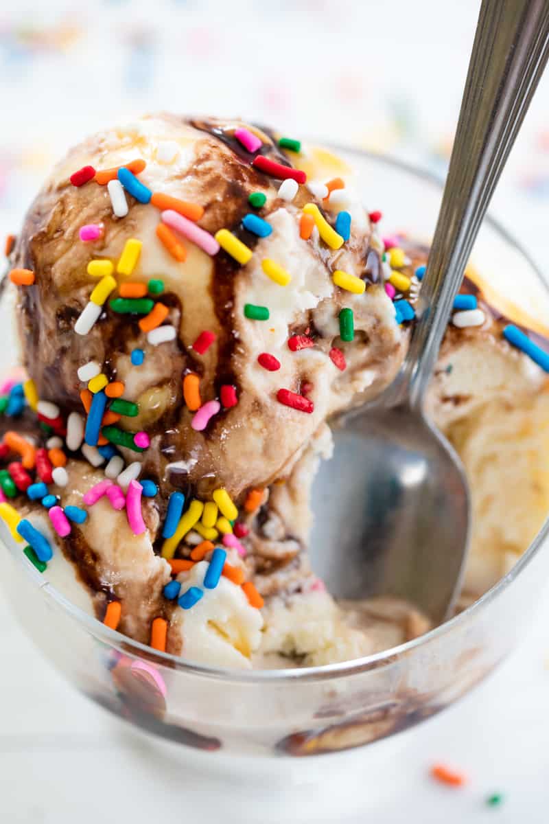 Homemade Ice Cream in a bowl with chocolate sauce and colorful sprinkles with a spoon
