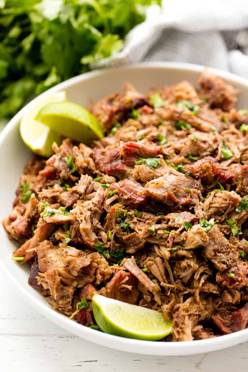 Smoked Pork Carnitas in a bowl with lime wedges