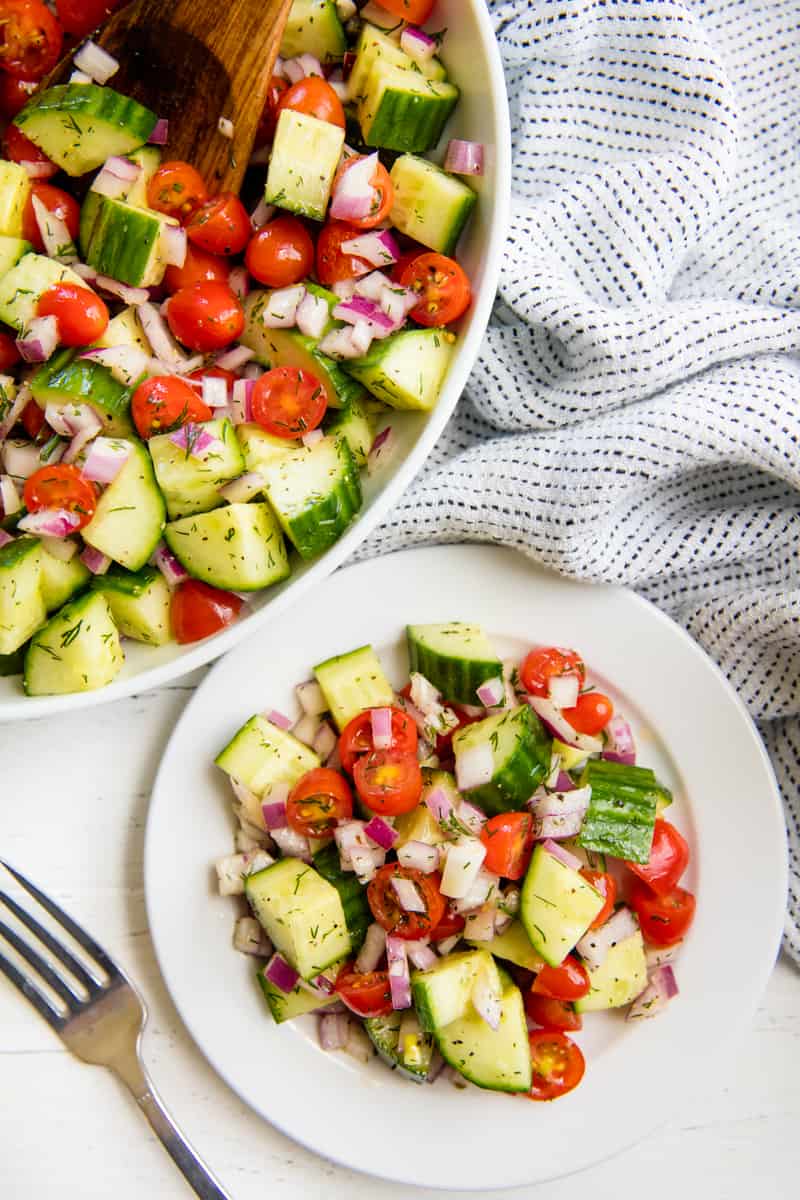 Cucumber and Tomato Salad tossed with lemon dill dressing and served on a plate
