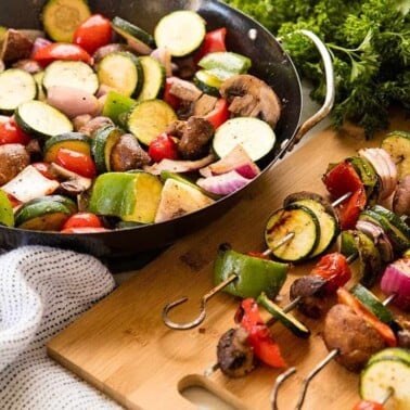 Grilled vegetables in a skillet and on skewers.