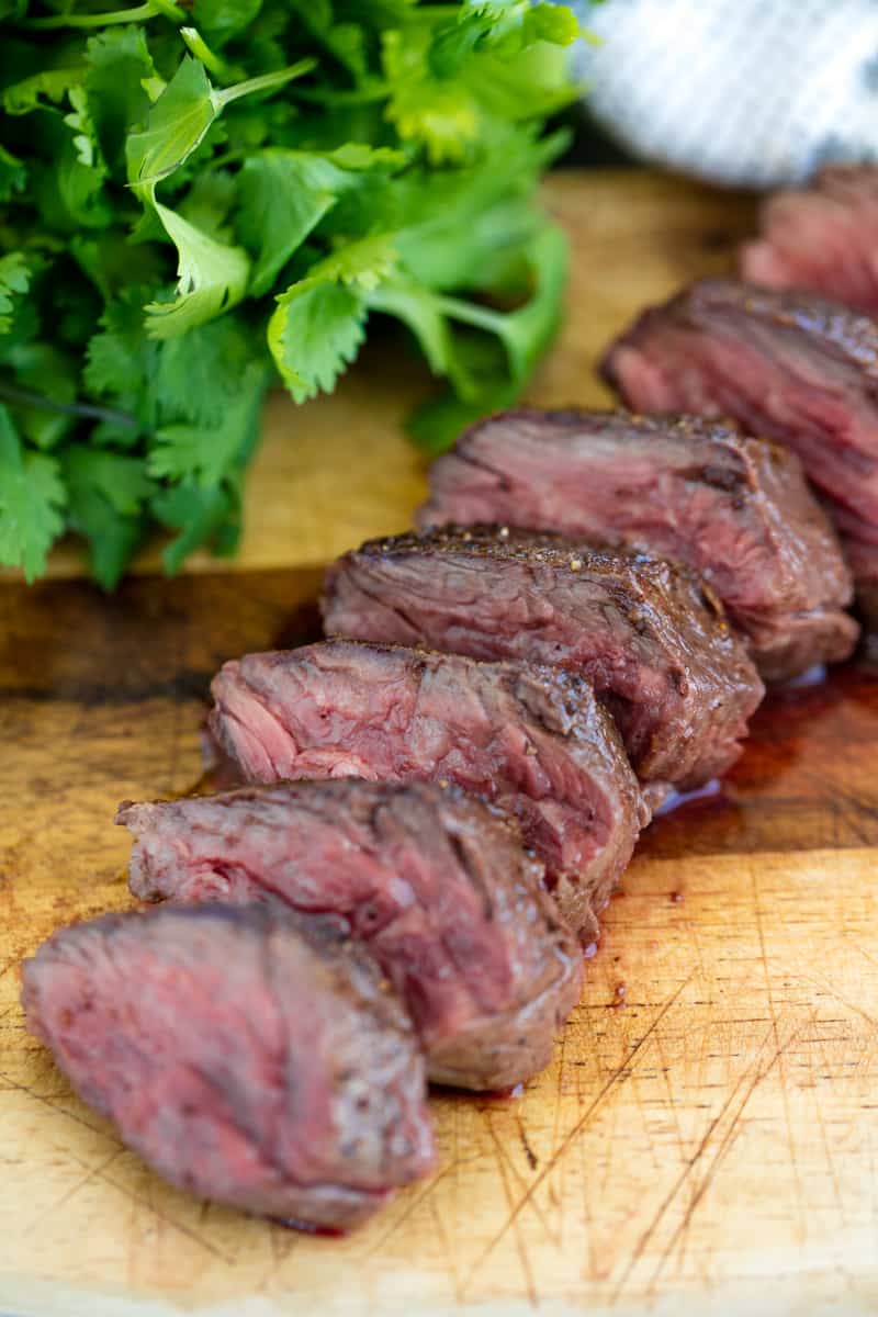 A sliced up hanger steak on a cutting board.