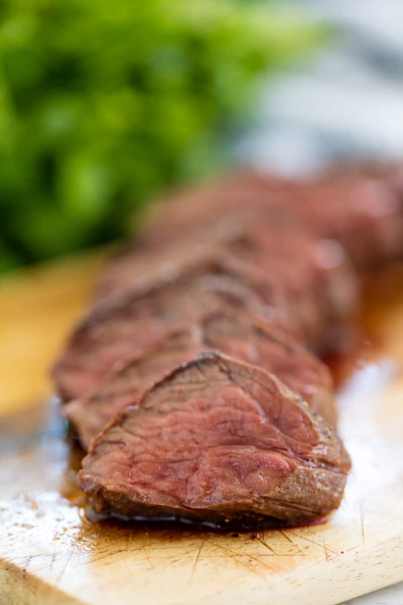 Close up of sliced up hanger steak on a cutting board.
