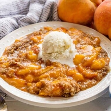 Peach crisp in a bowl with a scoop of ice cream