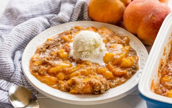 Peach crisp in a bowl with a scoop of ice cream
