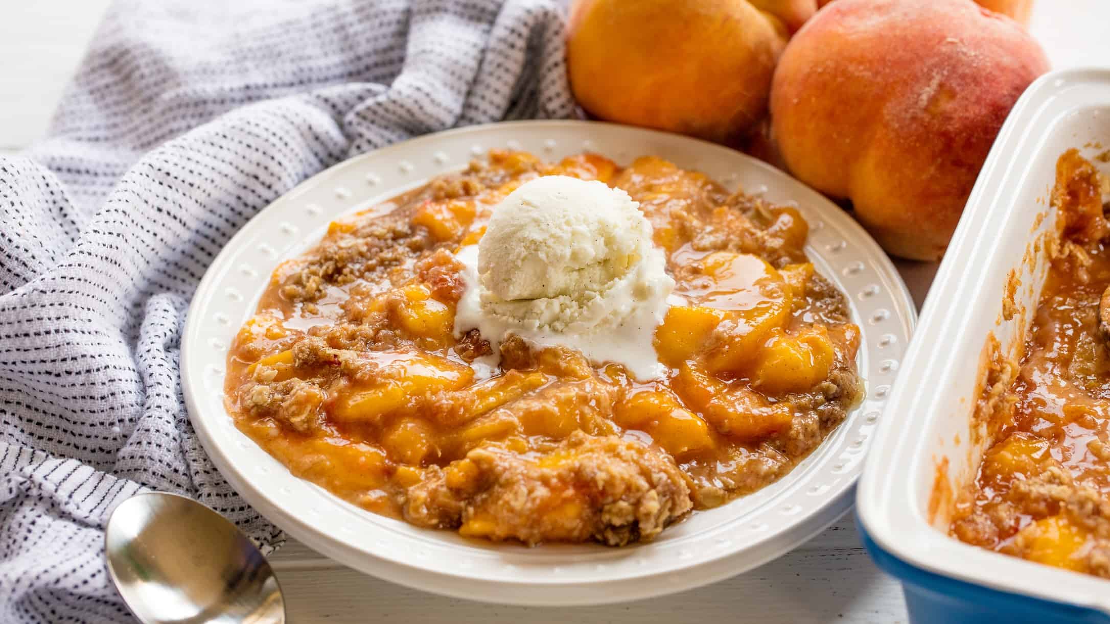 Peach crisp in a bowl with a scoop of ice cream