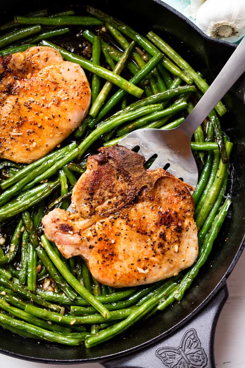 Bird's eye view of Pork Chops and Green Beans in a cast-iron skillet.