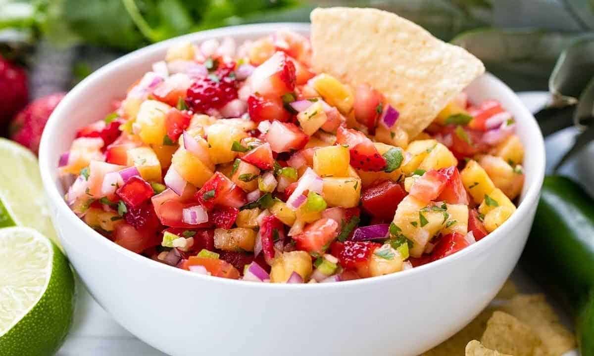 Strawberry Pineapple salsa in a white bowl with a chip in it.