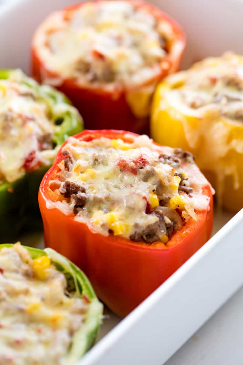 Stuffed Bell Peppers topped with cheese sitting in a white pan.