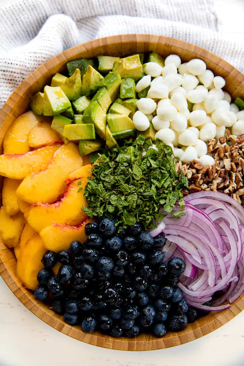 Bird's eye view of Peach Salad with all its toppings separated in a wooden bowl. 