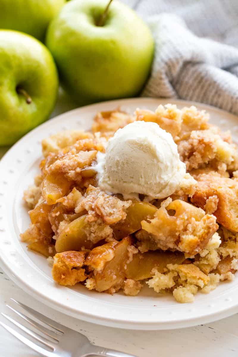 Served up apple cobbler on a white plate with a scoop of ice cream on it.