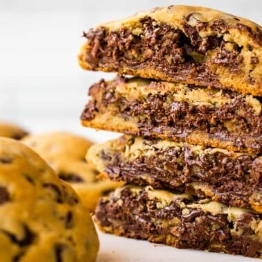 A stack of cut in halve bakery-style chocolate chip cookies.