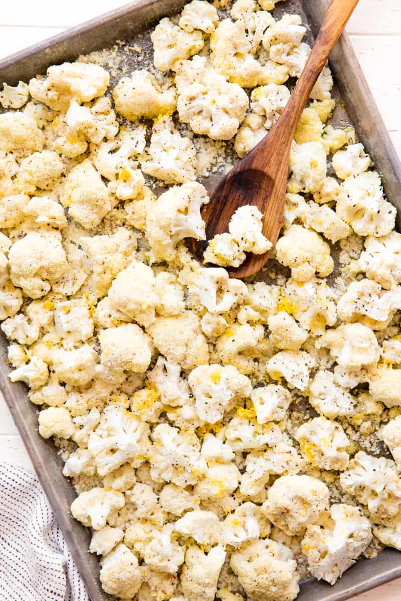 Roasted Cauliflower on a baking sheet with a wooden spoon on it.