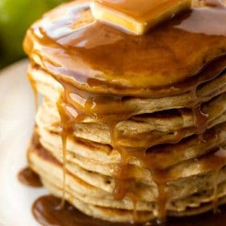 Stack of Apple Pancakes on a white plate topped with a pad of butter and syrup.