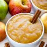 Applesauce in a white bowl with a cinnamon stick in it.