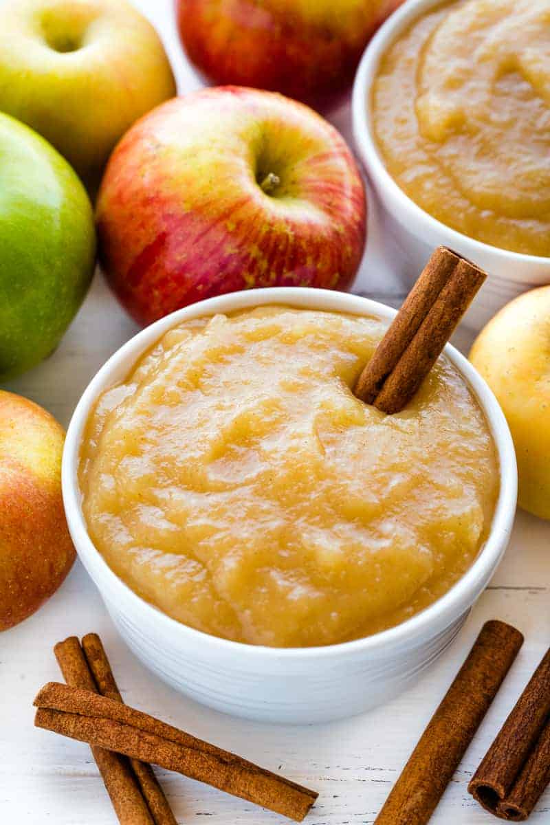 Applesauce in a white bowl with a cinnamon stick in it.