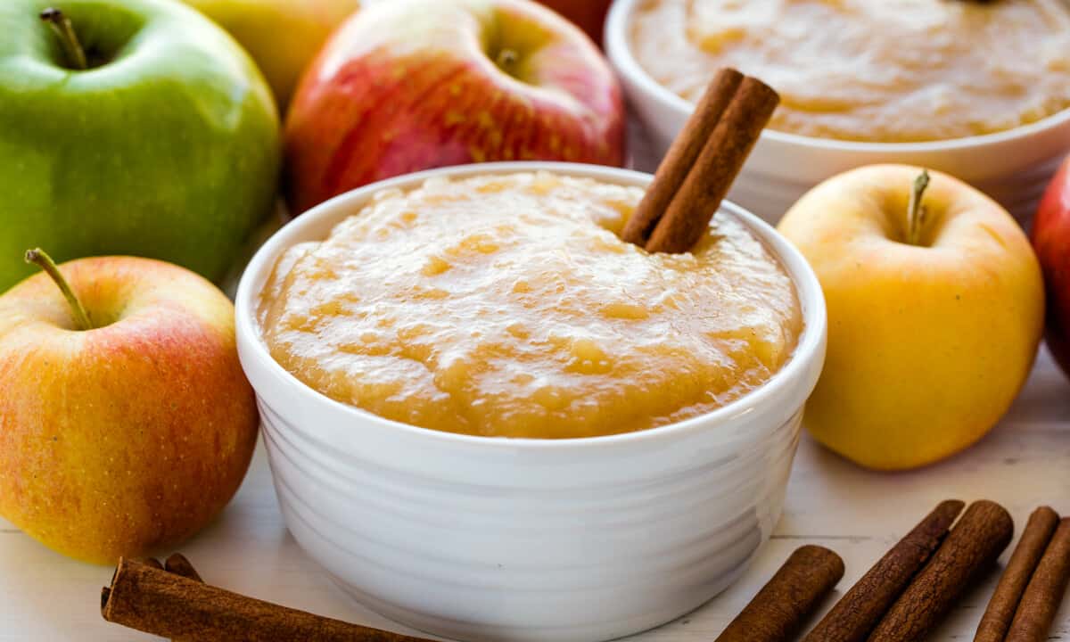 Applesauce in a white bowl with a cinnamon stick in it.