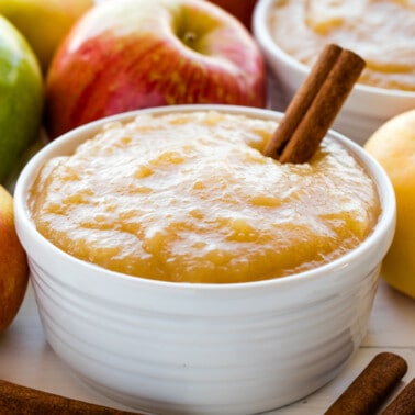 Applesauce in a white bowl with a cinnamon stick in it.