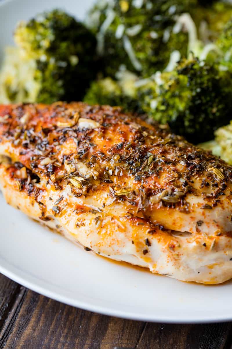 An herb stuffed chicken breast on a plate with broccoli.