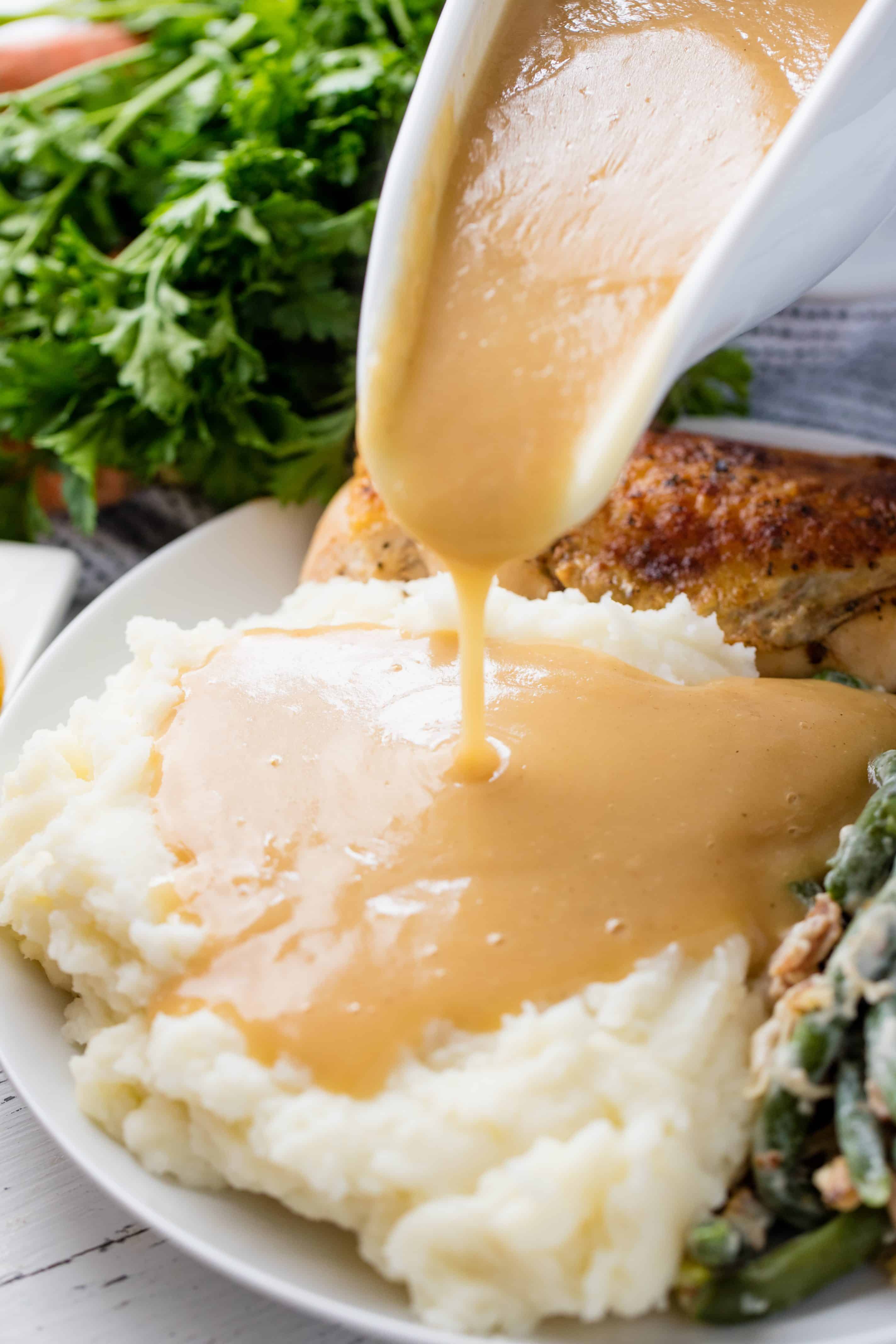 Gravy being poured onto some mashed potatoes. 