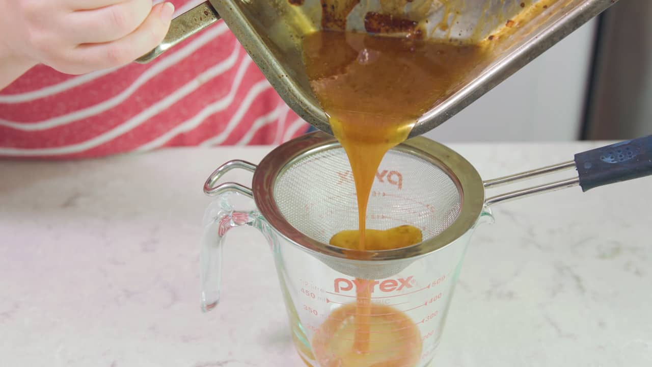 Pan Drippings getting filtered into a measuring cup.