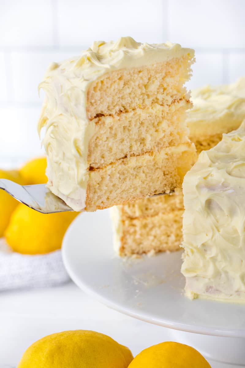 A slice of Lemon Cake being removed from the rest of the cake.