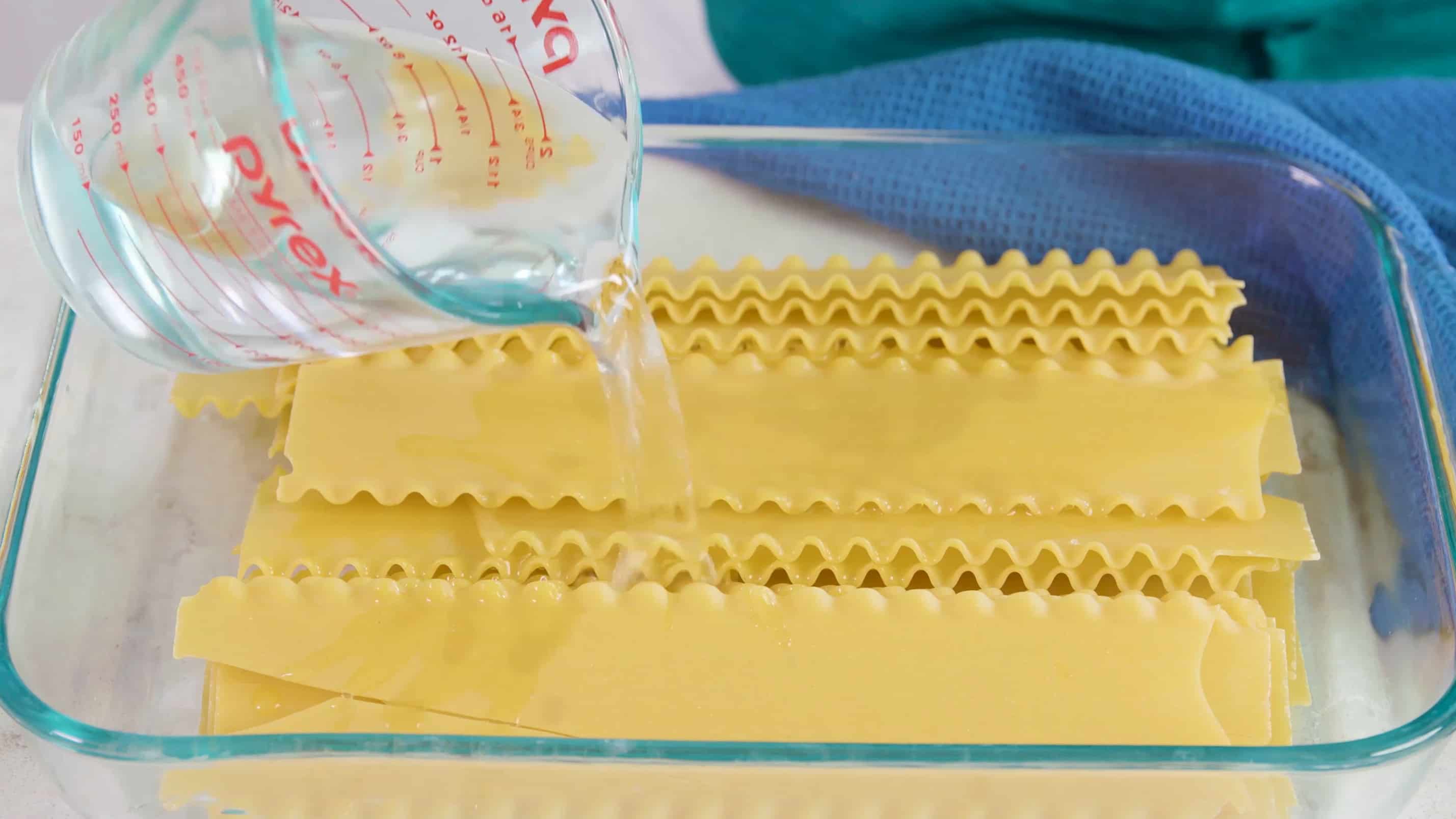 Water being poured into a pan full of lasagna noodles.