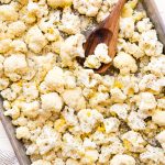 Roasted Cauliflower on a baking sheet with a wooden spoon on it.