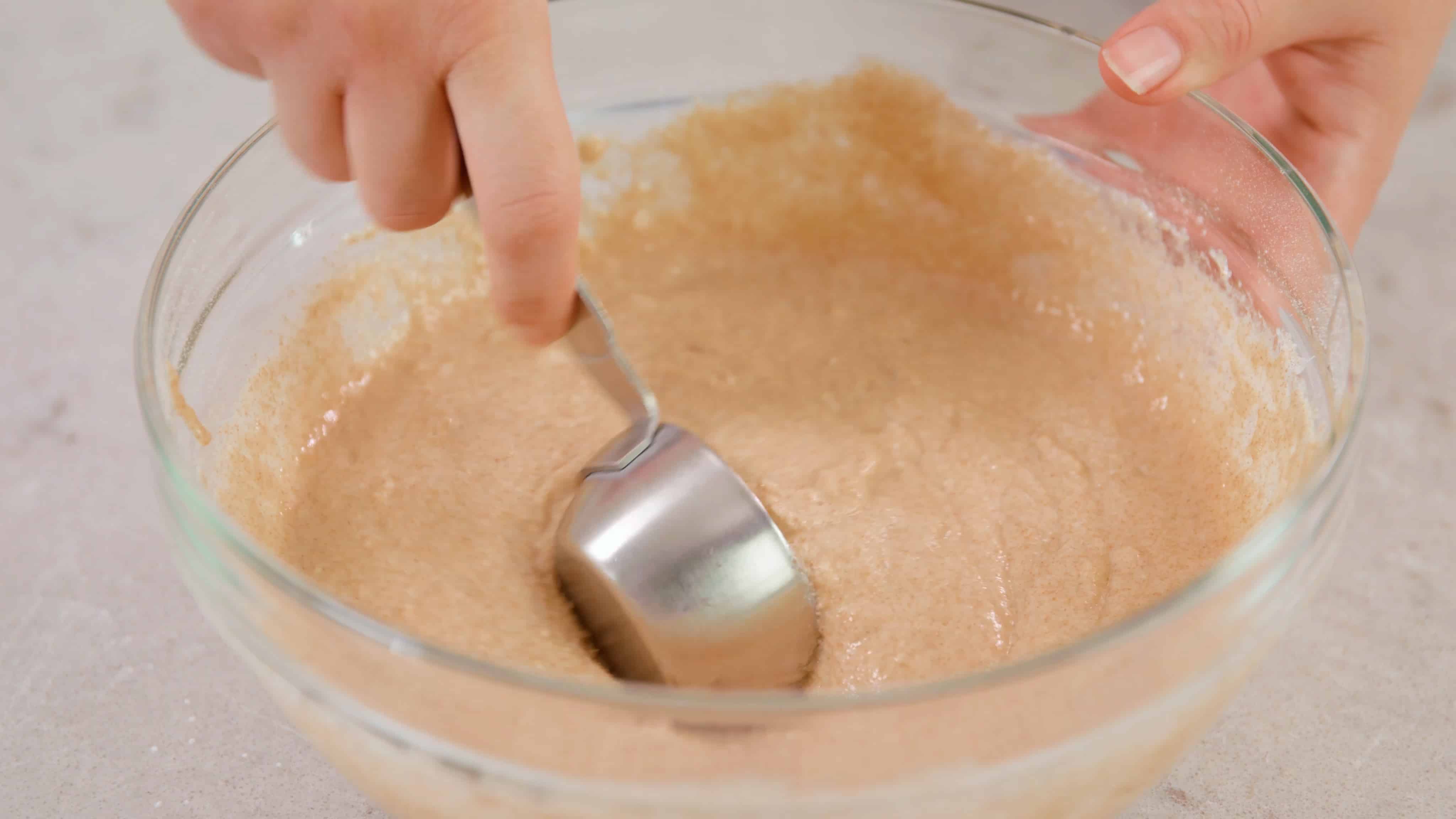 Whole Wheat Pancake Batter being scooped by a quarter cup measuring cup.
