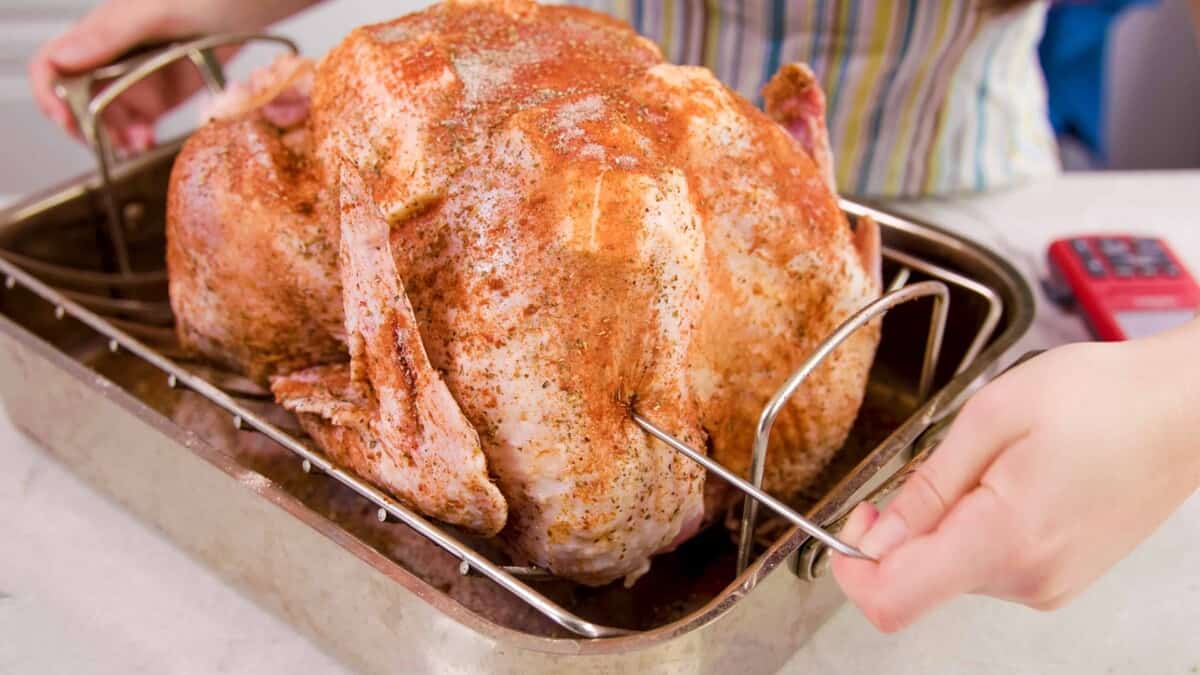 An image showing where to insert the probe of a thermometer into the thickest part of the turkey breast.