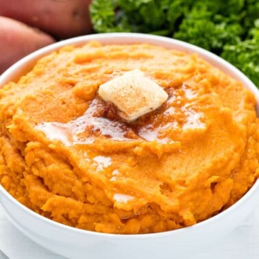 Mashed sweet potatoes in a bowl topped with cinnamon honey butter