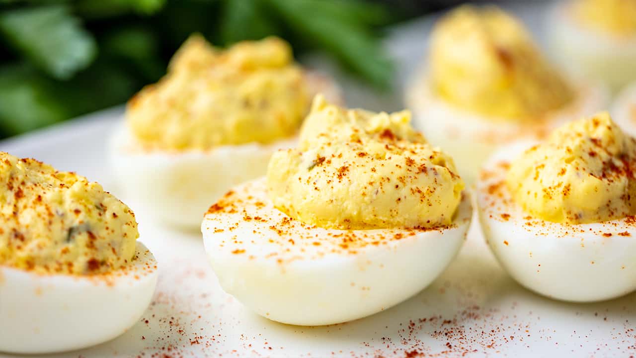 Deviled Eggs sprinkled with cayenne pepper on a white plate.