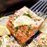 Salmon being lifted out of a skillet with a spatula.