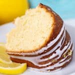 A slice of lemon pound cake on a white plate with a slice of lemon.