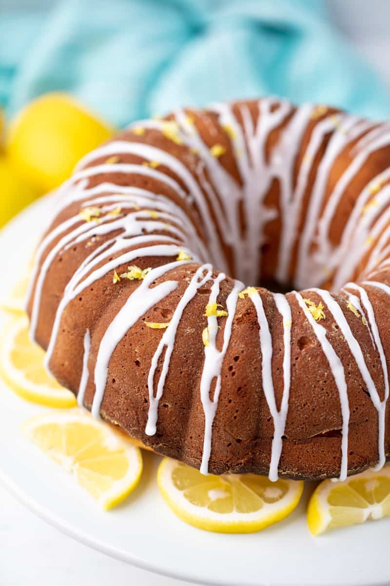 Lemon Pound Cake on a cake stand with lemon slices on it.