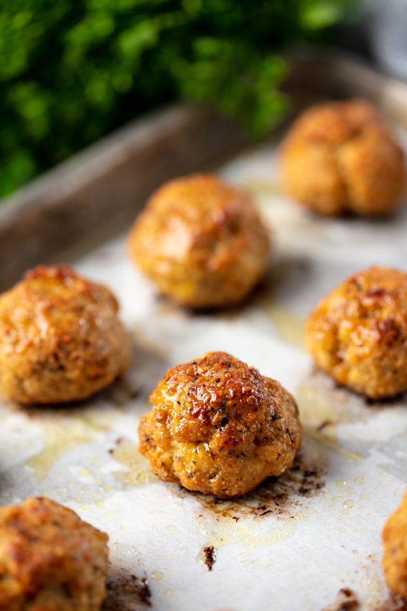 Baked Chicken Meatballs on parchment paper on a baking sheet.