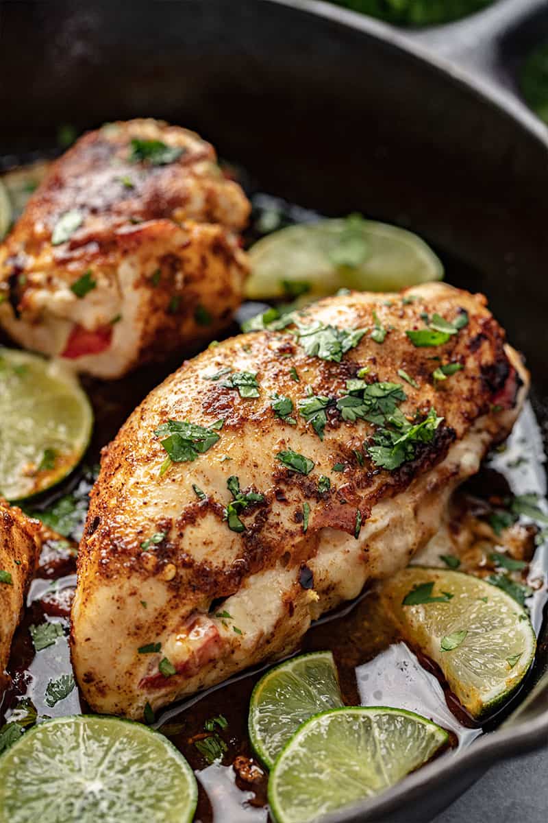 Fajita Stuffed Chicken in a skillet with sliced limes