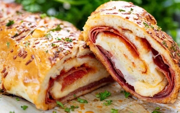 Stromboli cut in half to show cross-section of meat and cheese.