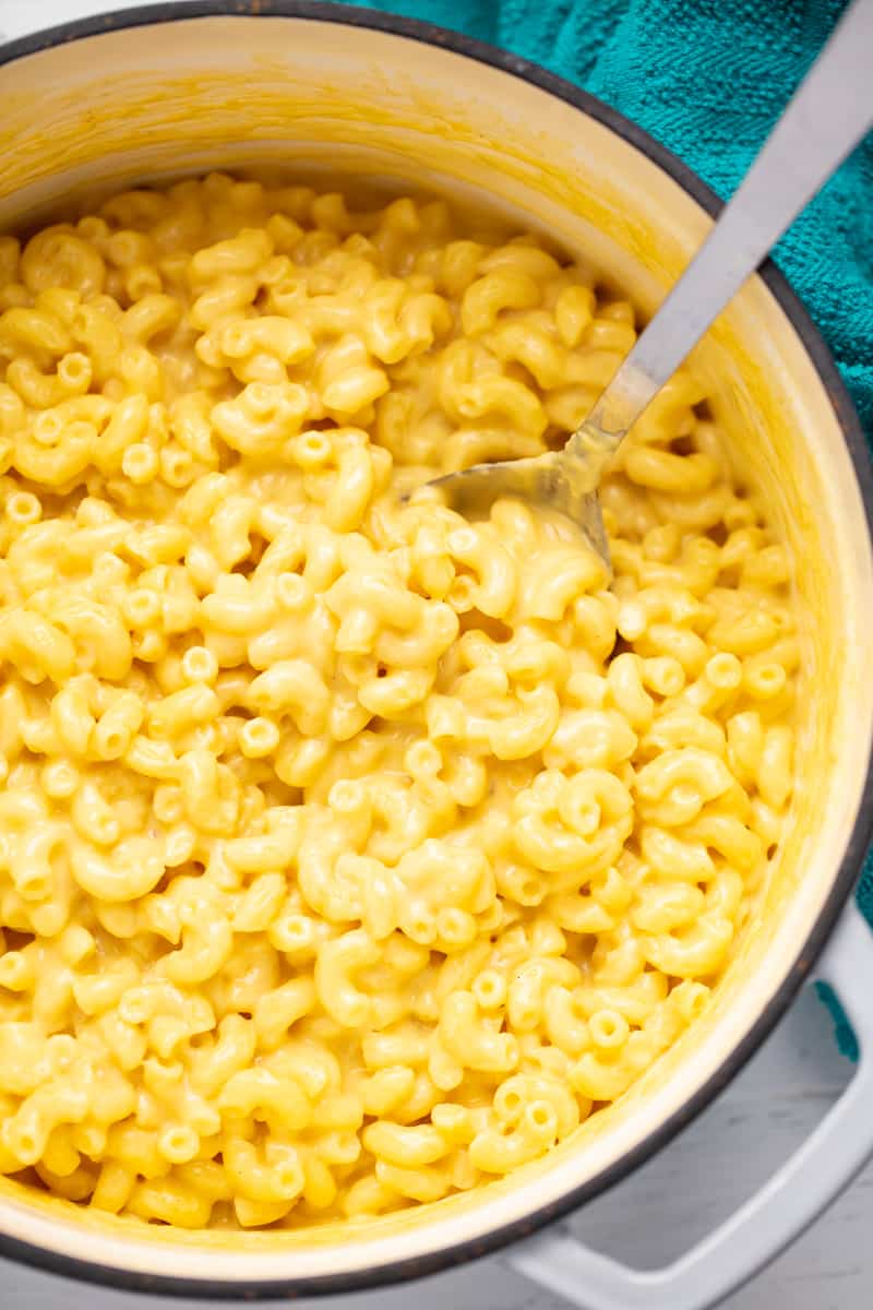 Bird's eye view of mac and cheese in a ceramic pot with a metal spoon in it.