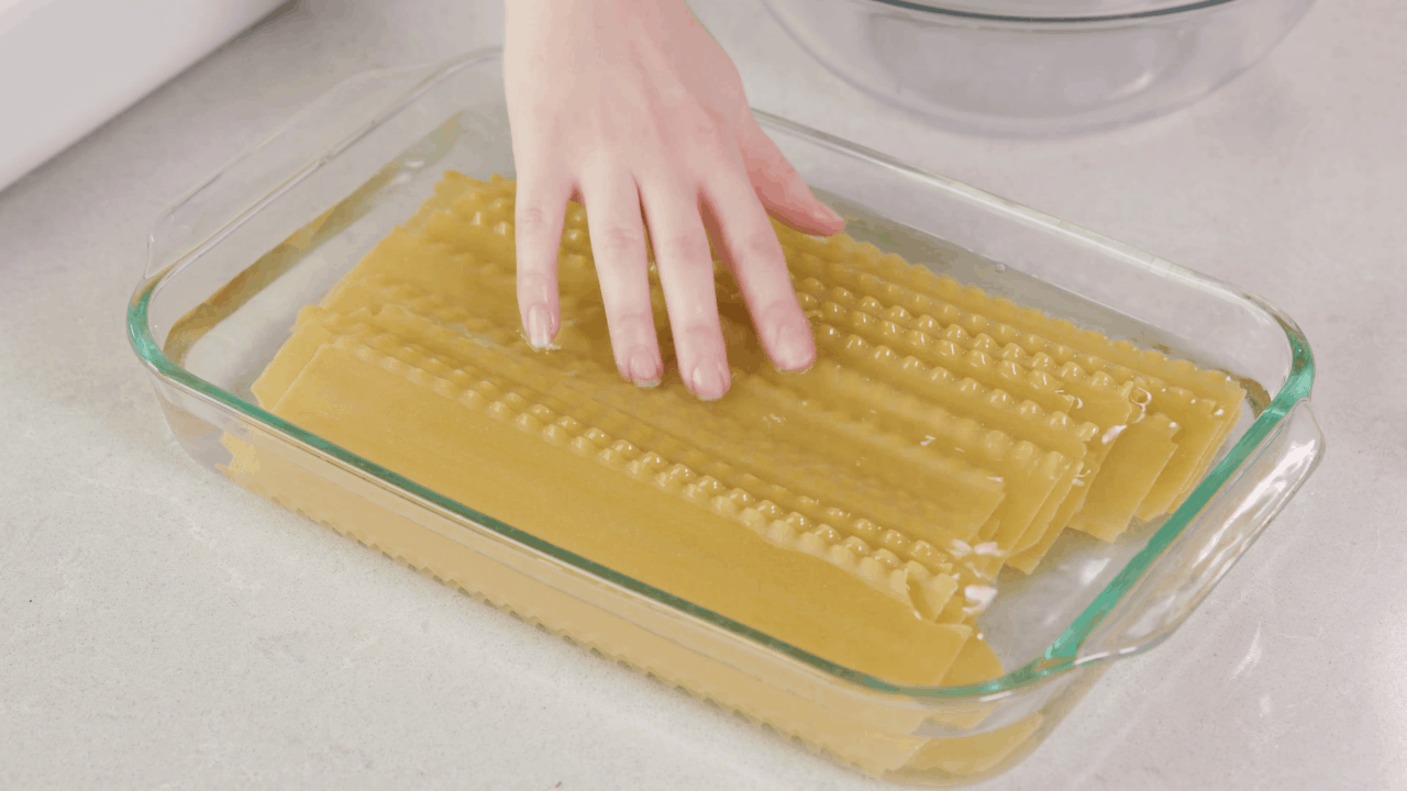 Lasagna noodles in a glass baking dish covered with water.