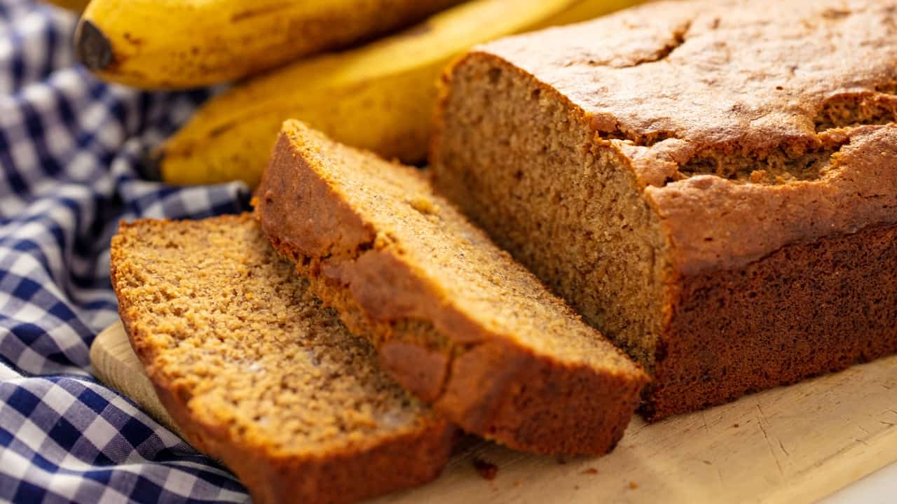 Banana Bread with two slices taken off the end, laying on each other all on a cutting board.